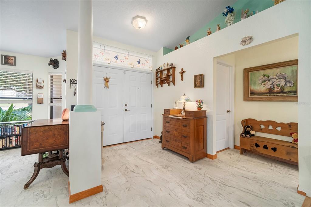 An entryway features a white double door, marble-look tile flooring, and a wooden chest — 1472 IVYDALE ROAD, SPRING HILL, FL