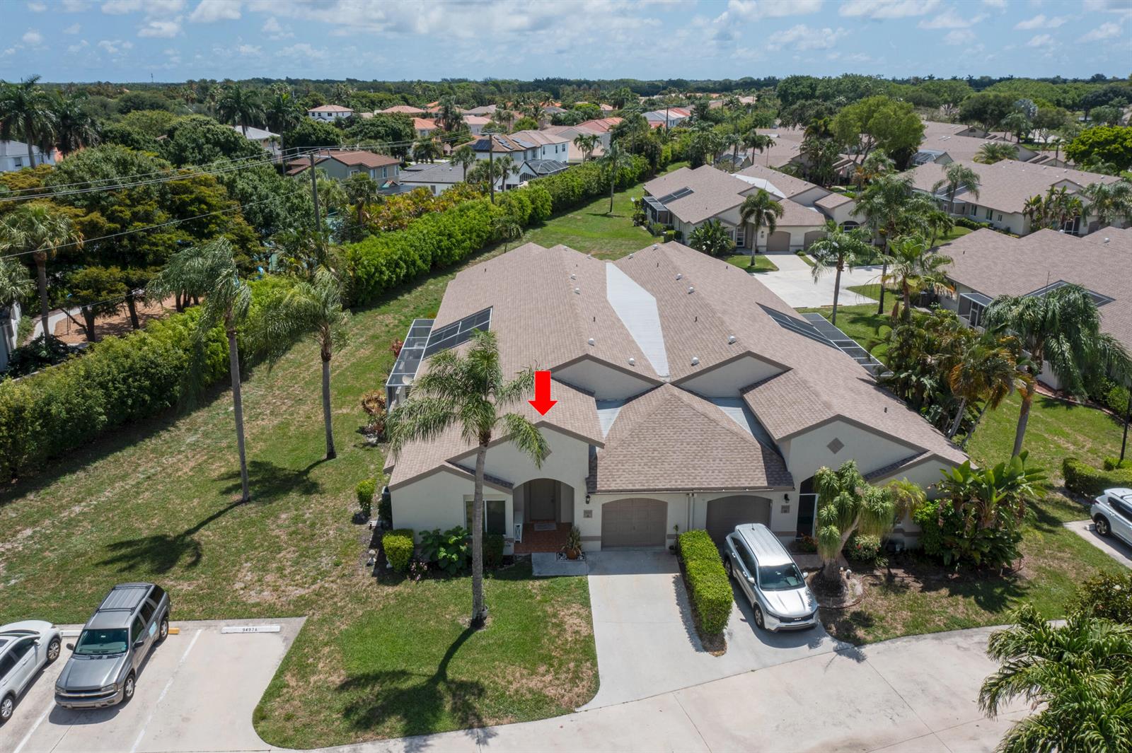 An aerial view shows a tan, multi-unit residential building with a red arrow pointing toward an entrance — 9497 Boca Gardens Parkway # A, Boca Raton FL 33496, BOCA RATON, FL