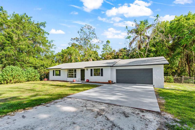 A single-story white house with a gray garage door and a concrete driveway — 11852 N 47th Rd Road N, FL 33411, FL