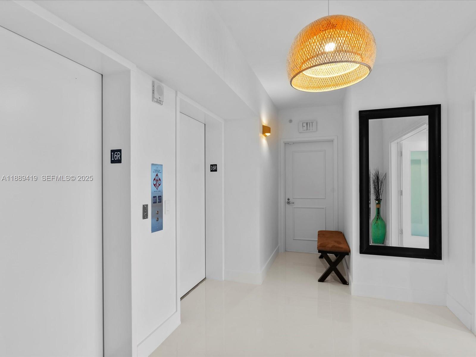 A bright hallway features white walls, two elevator doors, a wooden pendant light, and a mirror — 3101 S Ocean Dr # 1608, Hollywood FL 33019, HOLLYWOOD, FL