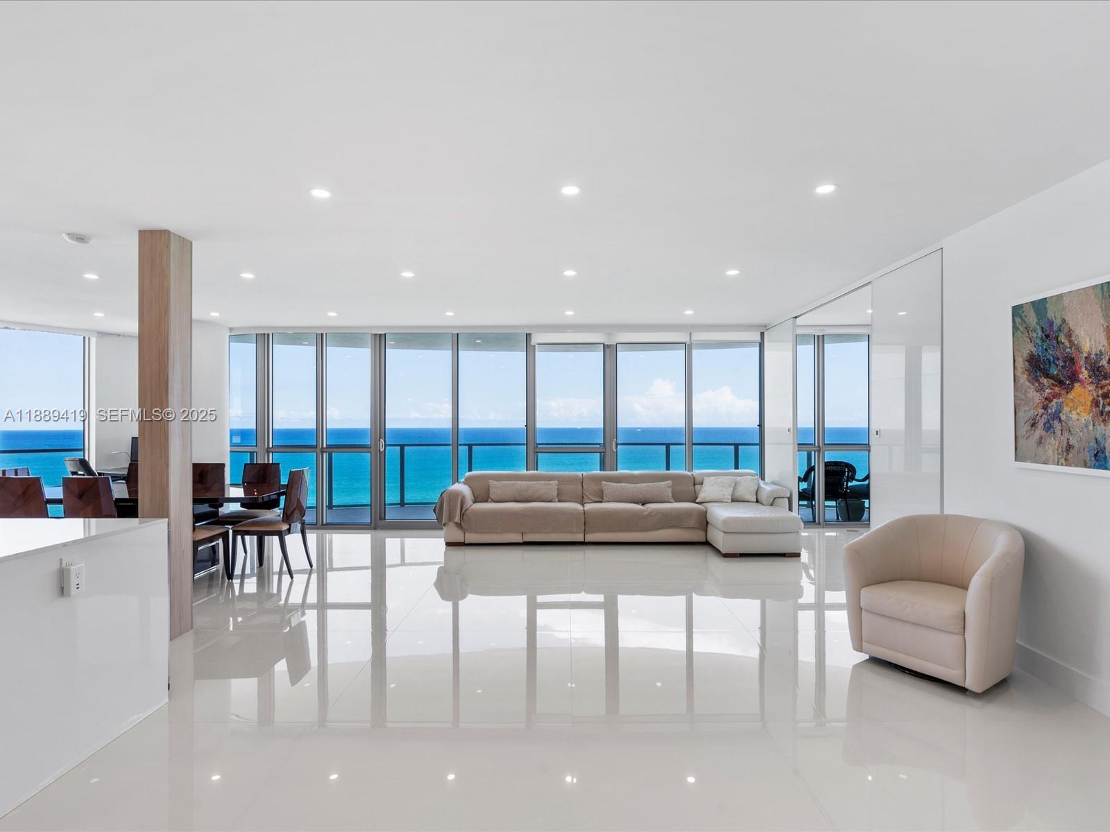 A modern living room features white tile floors, a large sectional sofa, and floor-to-ceiling windows — 3101 S Ocean Dr # 1608, Hollywood FL 33019, HOLLYWOOD, FL