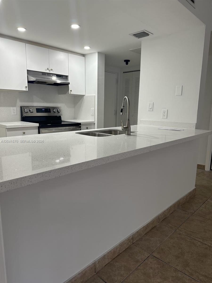 A kitchen features white cabinets, a stainless steel stove, and a white quartz countertop island — 8100 Geneva Ct # 142, Doral FL 33166, DORAL, FL