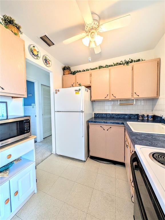 A kitchen features light wood cabinets, a white refrigerator, blue countertops, and a ceiling fan — 5951 TODD STREET UNIT D37, BRADENTON, FL