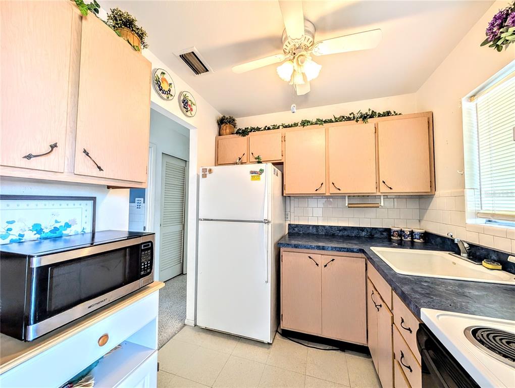 A kitchen features light wood cabinets, blue countertops, a white refrigerator, and a microwave — 5951 TODD STREET UNIT D37, BRADENTON, FL