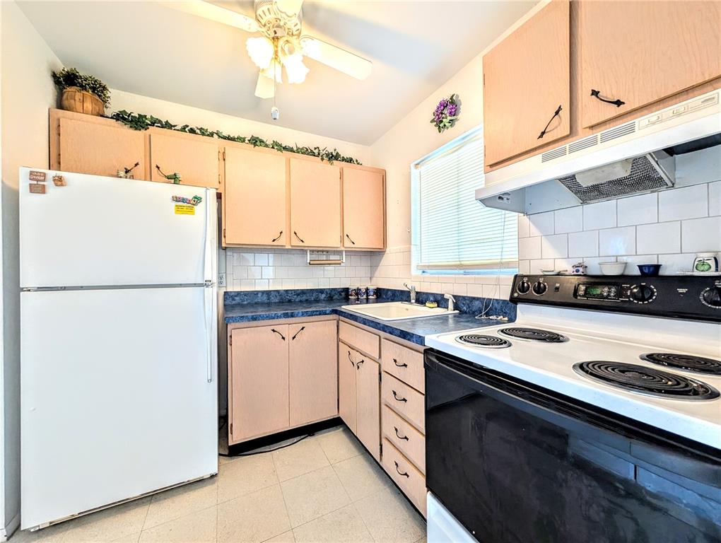 A kitchen features light wood cabinets, blue laminate countertops, white appliances, and a ceiling fan — 5951 TODD STREET UNIT D37, BRADENTON, FL