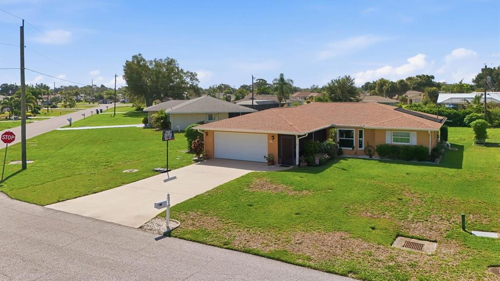 An exterior view of a single-story ranch-style house with a tan facade and brown roof — 911 GASPARILLA BOULEVARD, ENGLEWOOD, FL