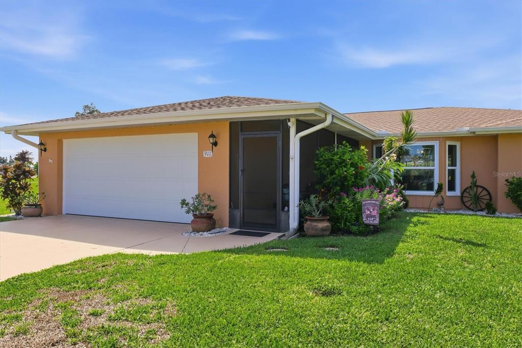 A single-story house with a two-car garage, a screened entryway, and a green lawn — 911 GASPARILLA BOULEVARD, ENGLEWOOD, FL