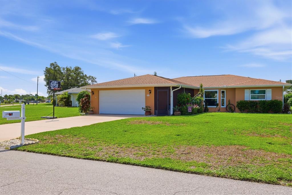 A single-story house with an orange exterior, a white garage door, and a grassy lawn — 911 GASPARILLA BOULEVARD, ENGLEWOOD, FL