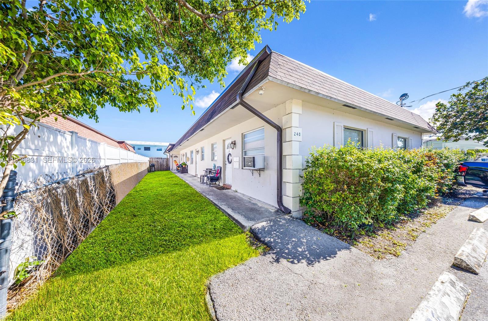 A single-story building exterior features a concrete walkway, a grassy lawn, and white walls — 240 SE 9th Ave, Pompano Beach FL 33060, POMPANO BEACH, FL