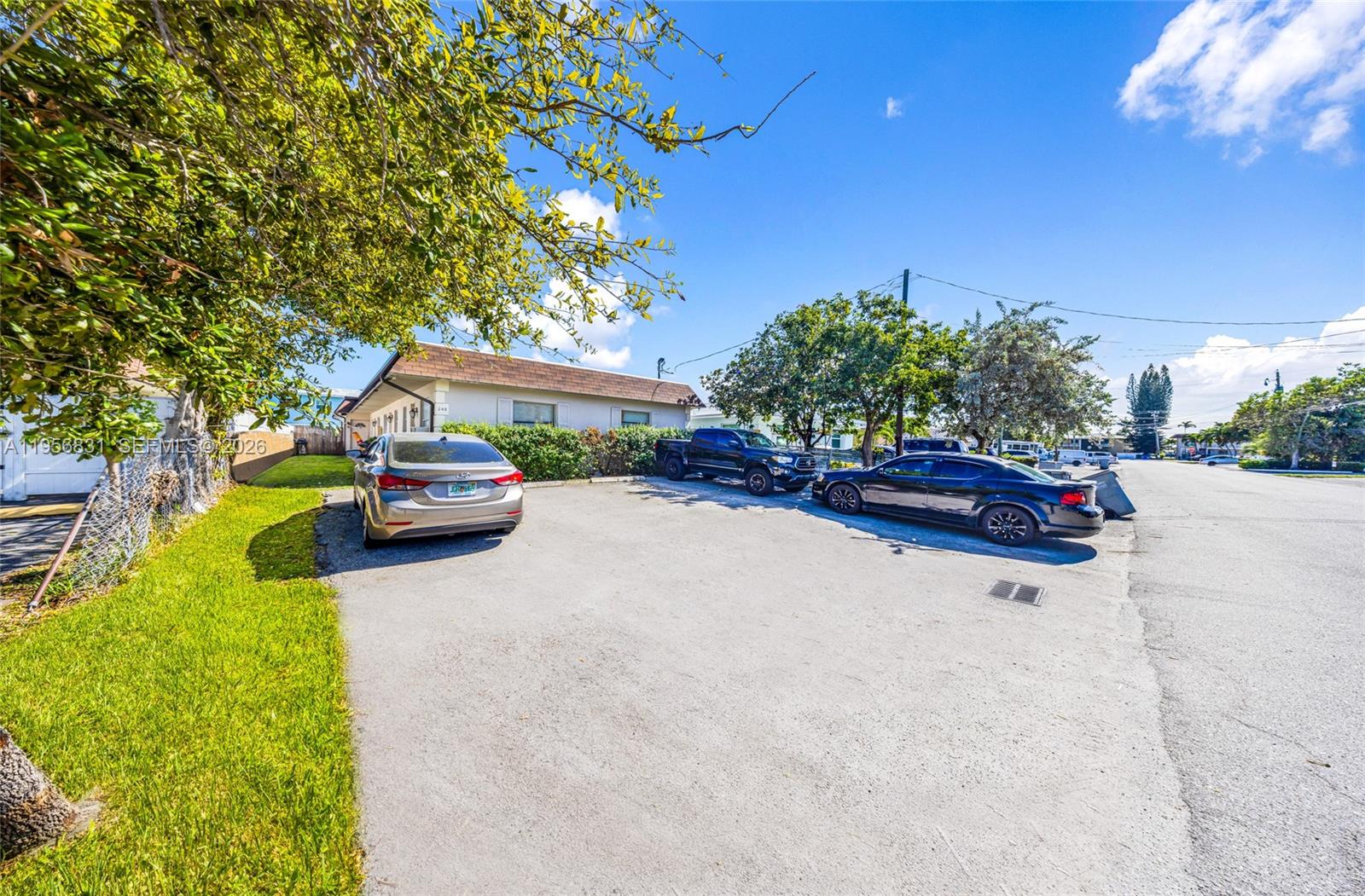 A single-story house with a paved driveway and three parked cars under a blue sky — 240 SE 9th Ave, Pompano Beach FL 33060, POMPANO BEACH, FL