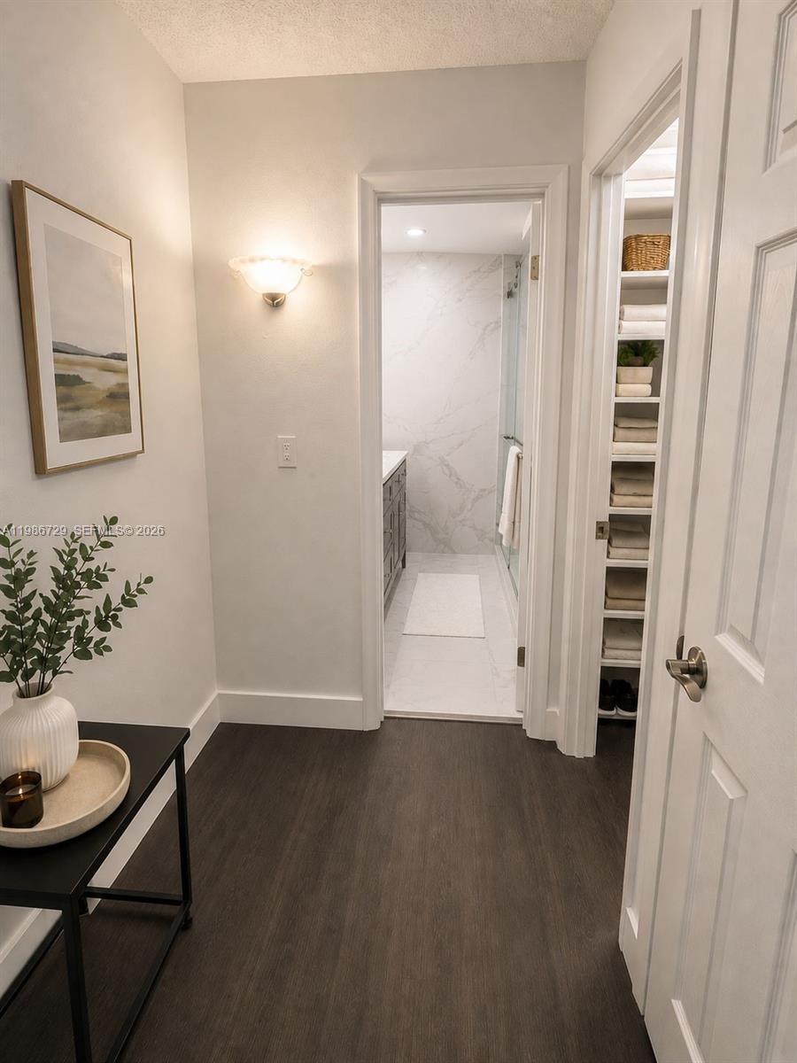 A hallway with dark flooring leads to a bathroom with a marble-tiled shower — 299 NW 52nd Ter # X, Boca Raton FL 33487, BOCA RATON, FL