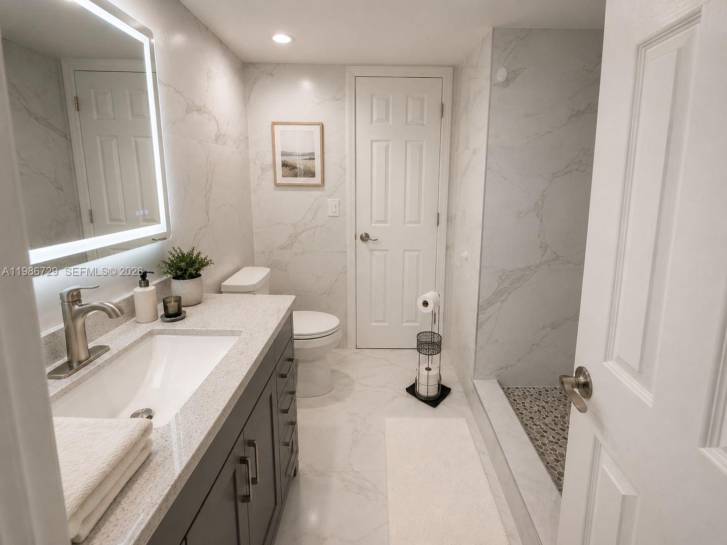 A modern bathroom features a dark vanity, marble-look tile walls, and a walk-in shower — 299 NW 52nd Ter # X, Boca Raton FL 33487, BOCA RATON, FL