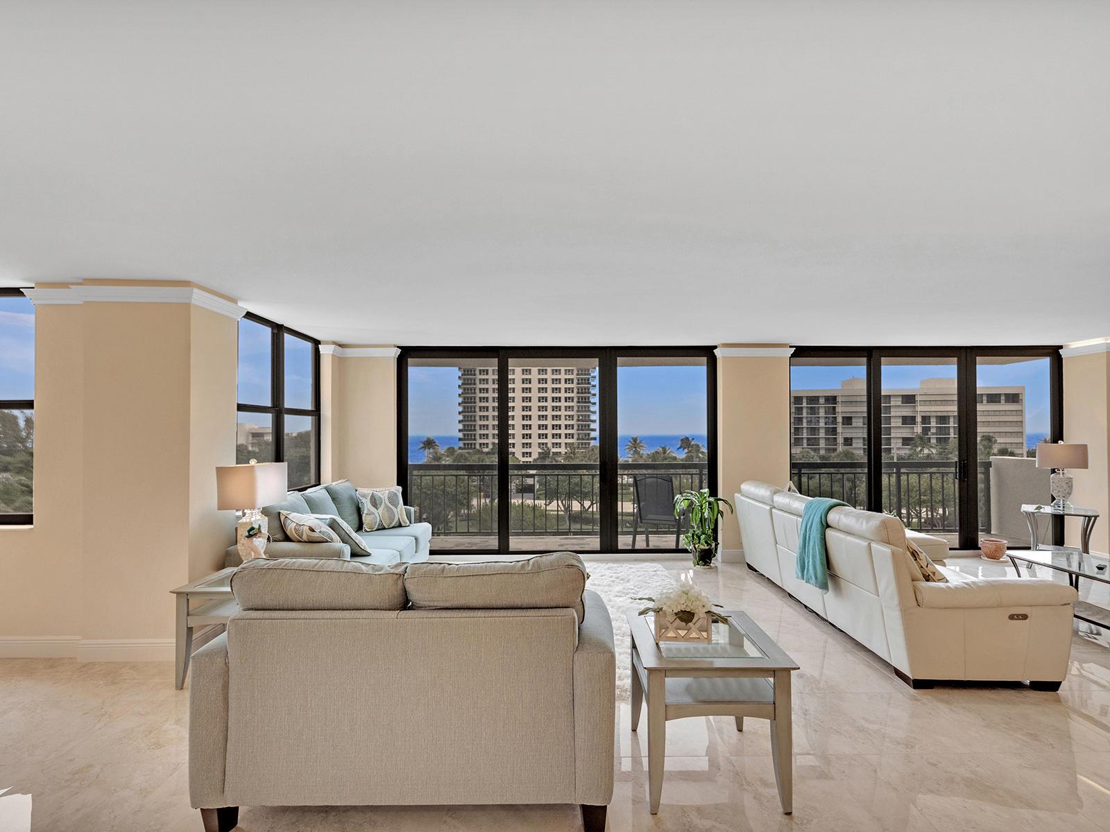 A spacious living room with light-colored furniture, marble floors, and large windows overlooking the ocean — 2003 N Ocean Boulevard # 602, Boca Raton FL 33431, BOCA RATON, FL