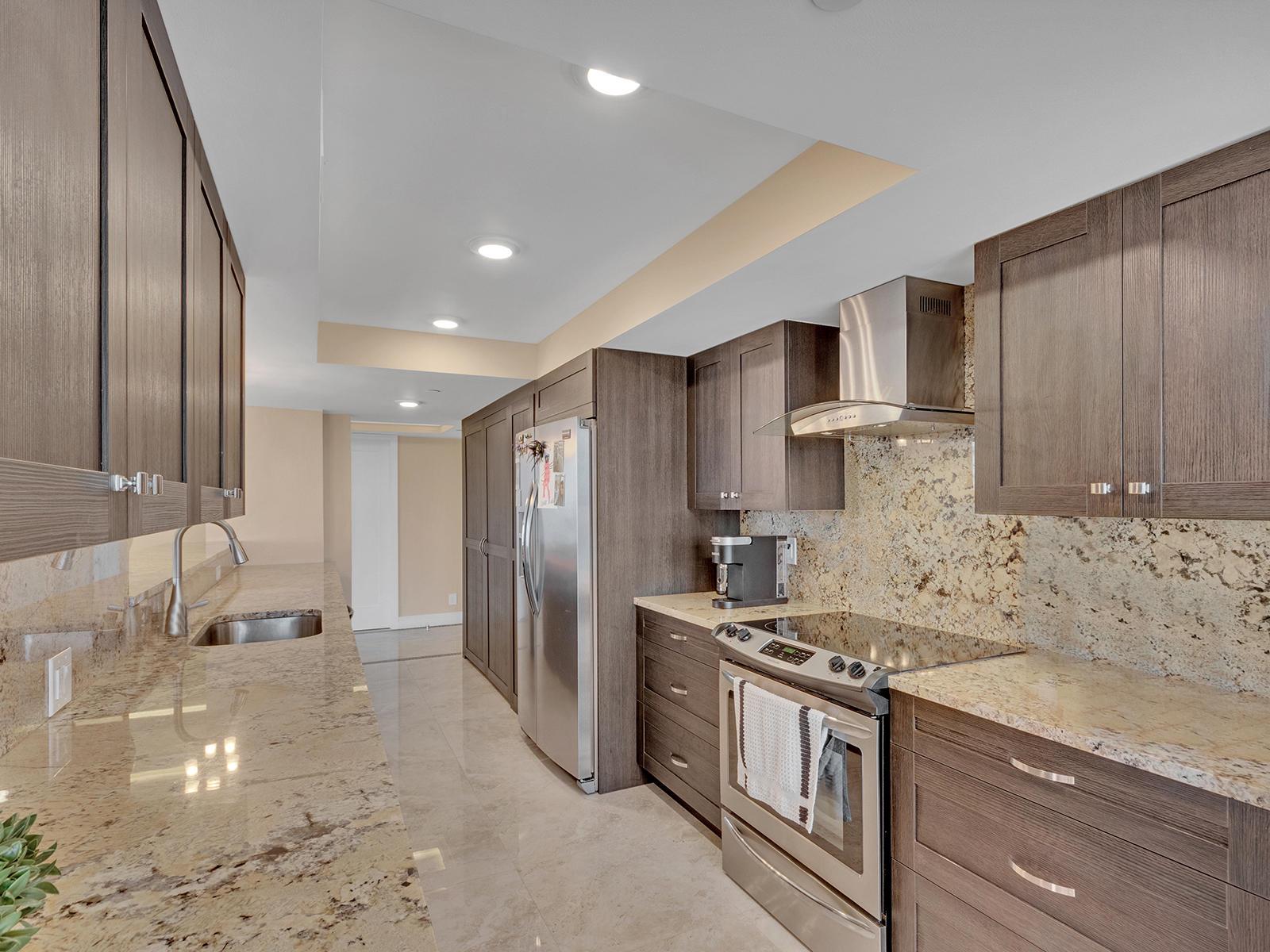 A modern kitchen features dark wood cabinets, granite countertops, stainless steel appliances, and tile flooring — 2003 N Ocean Boulevard # 602, Boca Raton FL 33431, BOCA RATON, FL