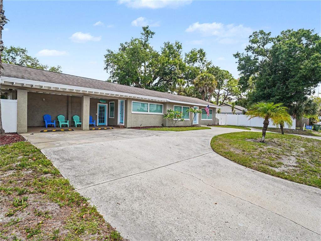 A single-story house with a concrete driveway, covered porch, and blue chairs — 2547 BAHIA VISTA STREET, SARASOTA, FL