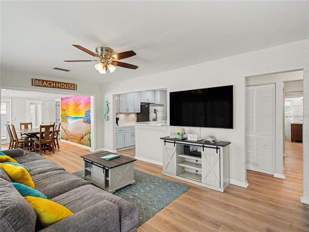 A living room features a grey sectional, a television, and a beach-themed mural — 2547 BAHIA VISTA STREET, SARASOTA, FL