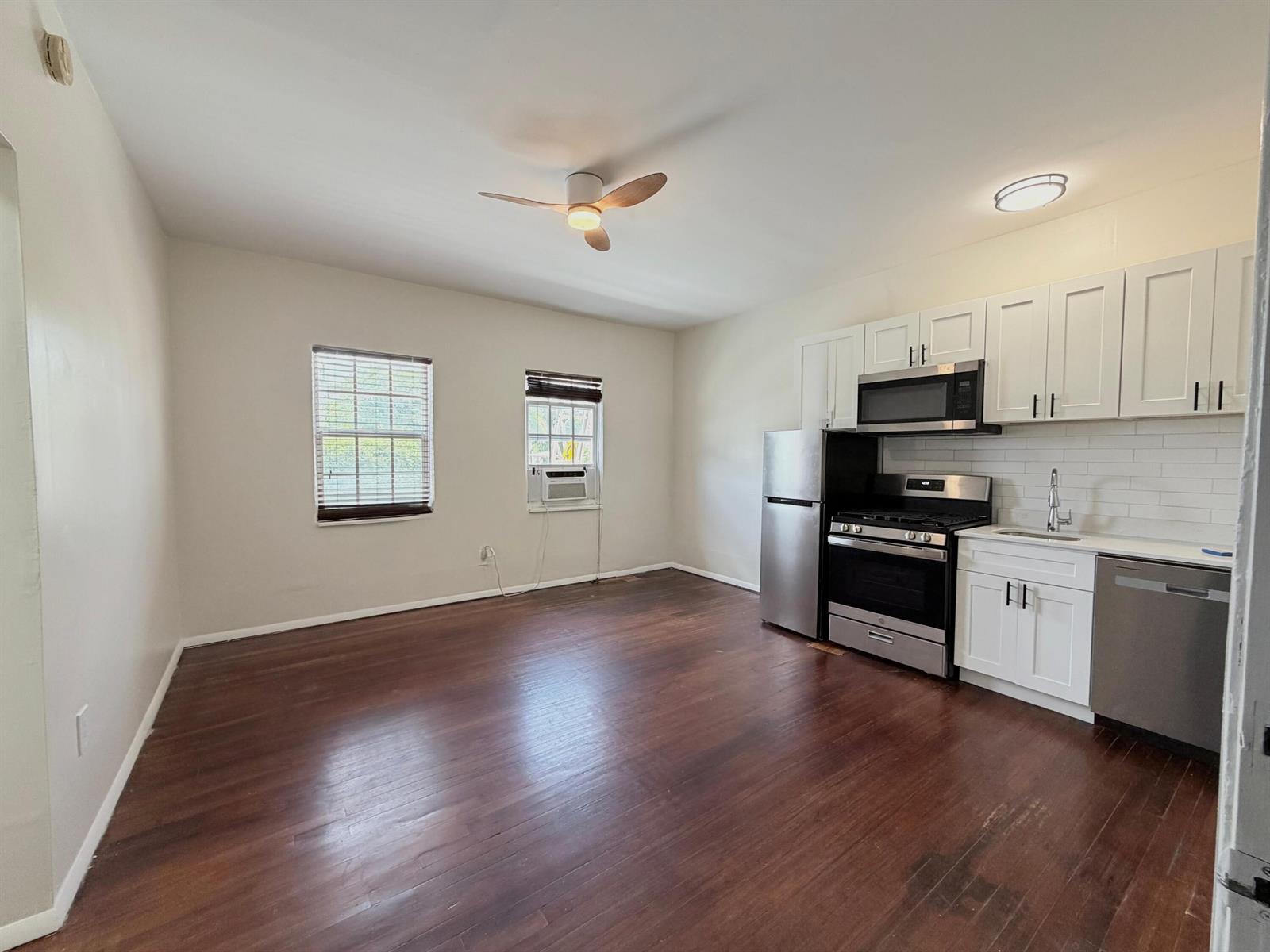 A kitchen and living area with dark hardwood floors, white cabinets, and stainless steel appliances — 623 Park Place Unit 5, West Palm Beach FL 33401, WEST PALM BEACH, FL