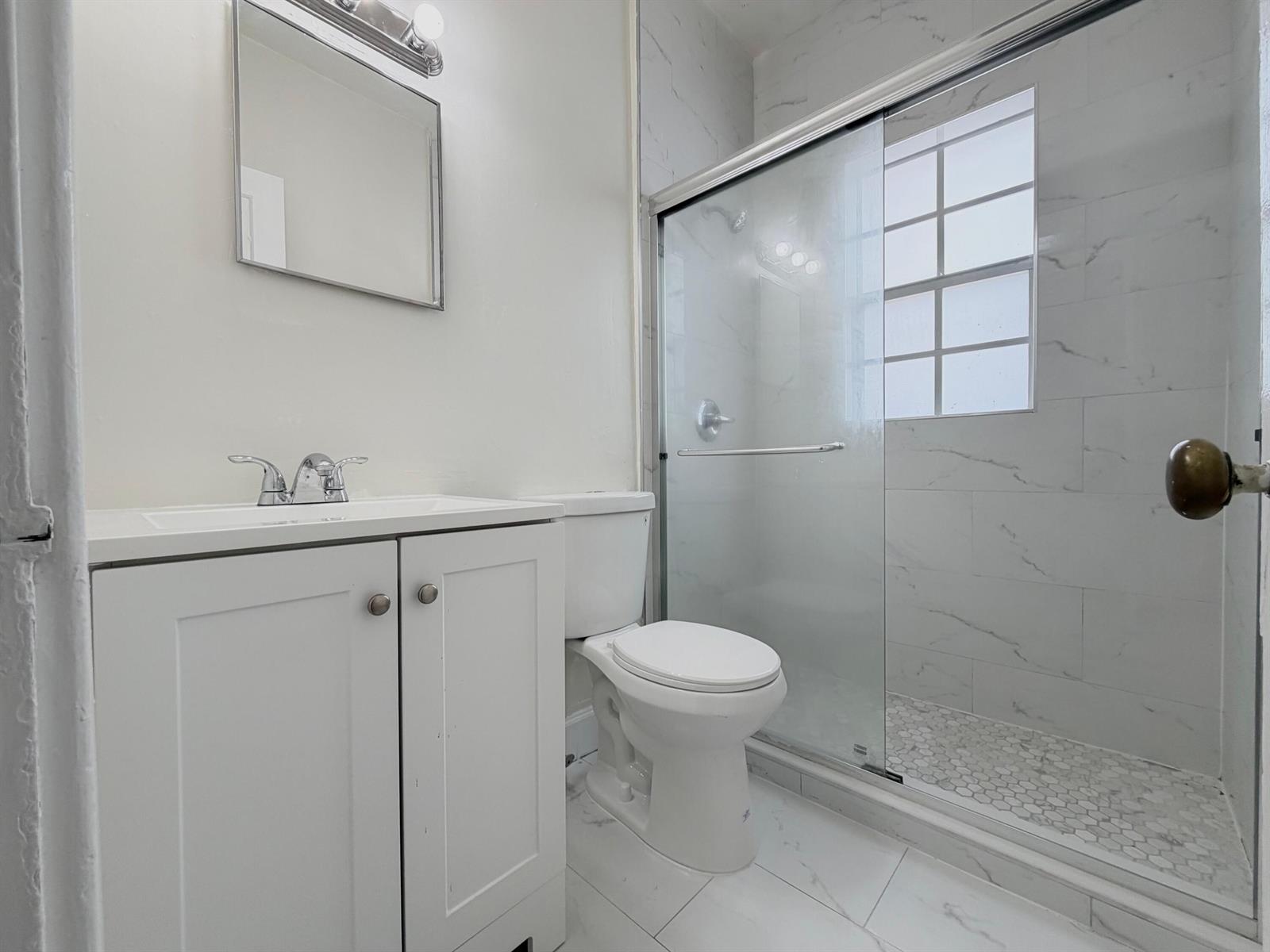 A bathroom features a white vanity, a toilet, and a glass-enclosed shower with tiled walls — 623 Park Place Unit 5, West Palm Beach FL 33401, WEST PALM BEACH, FL