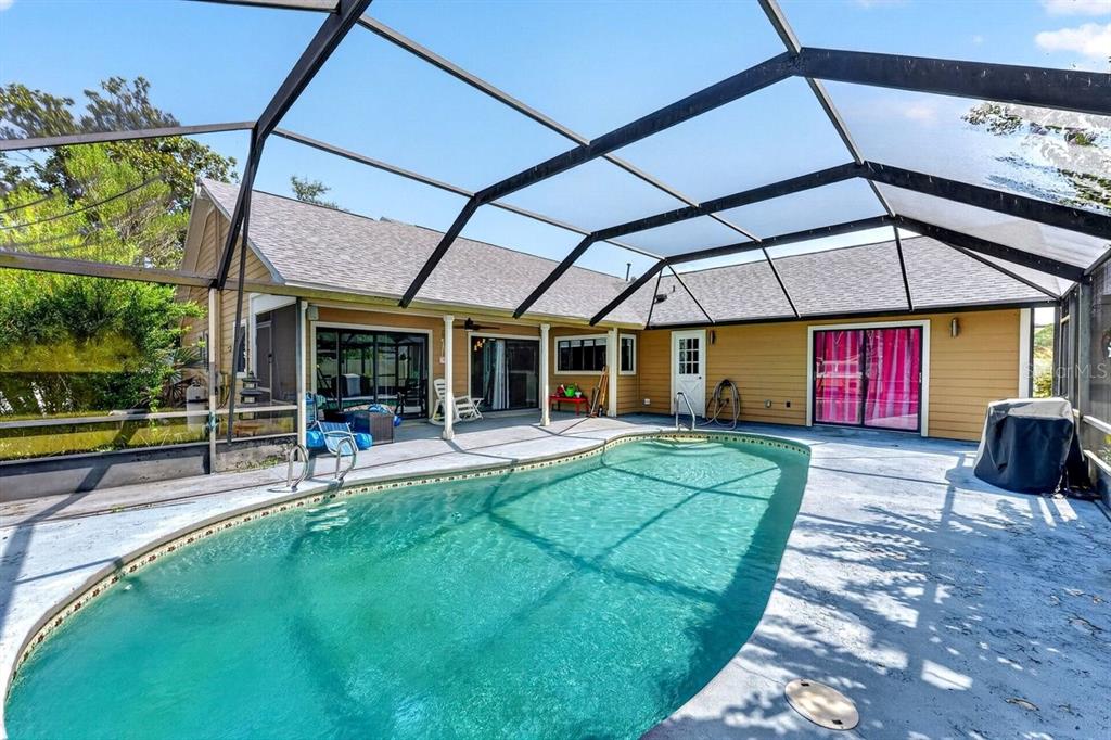 A swimming pool sits inside a screened-in patio area attached to a single-story house — 19 BIG DIPPER LANE, PALM COAST, FL