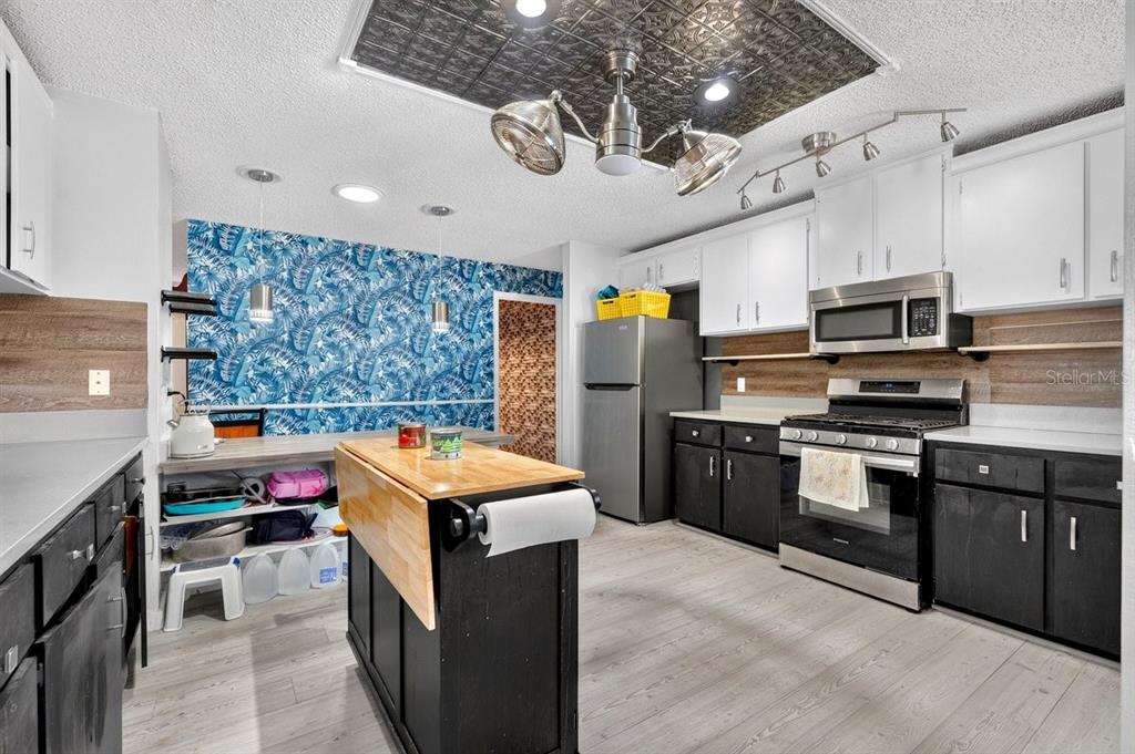 A kitchen features black lower cabinets, white upper cabinets, a kitchen island, and blue wallpaper — 19 BIG DIPPER LANE, PALM COAST, FL