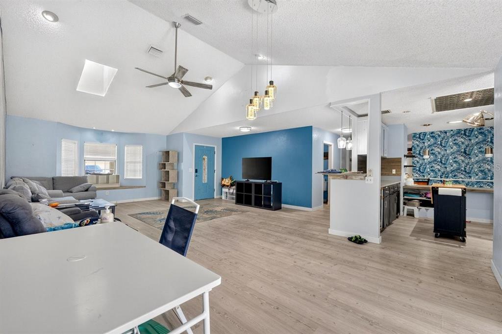 An open-concept living area features vaulted ceilings, light wood flooring, and a blue accent wall — 19 BIG DIPPER LANE, PALM COAST, FL
