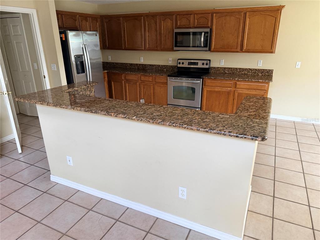 A kitchen features wood cabinets, granite countertops, stainless steel appliances, and a tiled floor — 443 OPAL COURT, ALTAMONTE SPRINGS, FL
