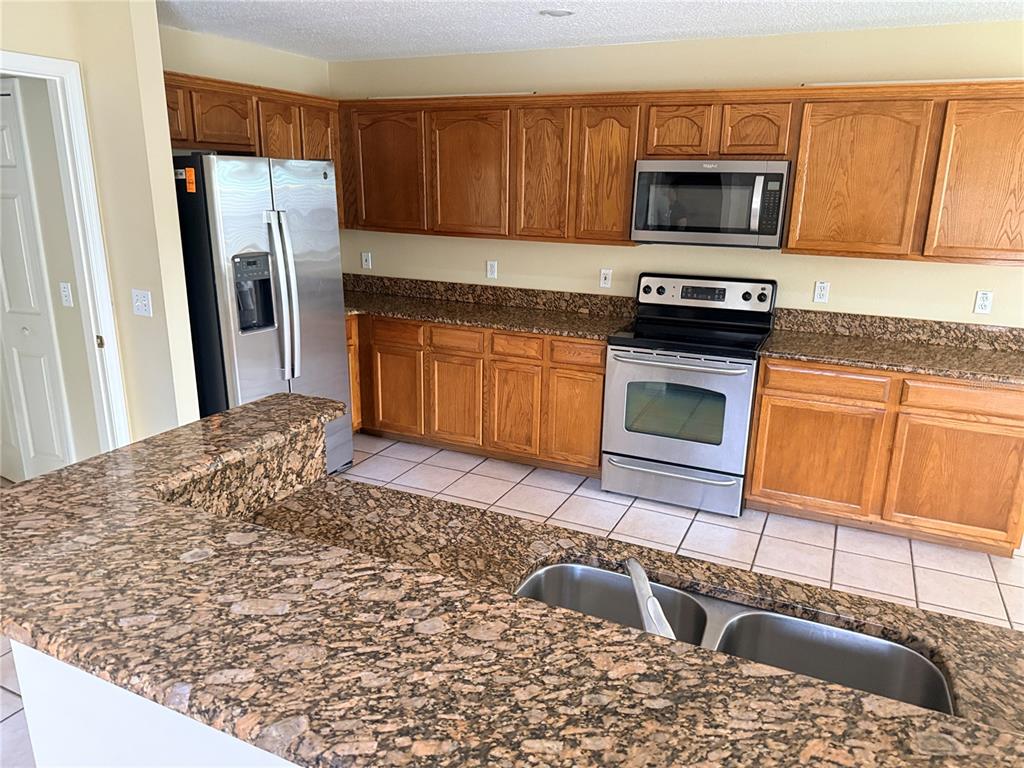 A kitchen features oak cabinets, granite countertops, stainless steel appliances, and tile flooring — 443 OPAL COURT, ALTAMONTE SPRINGS, FL