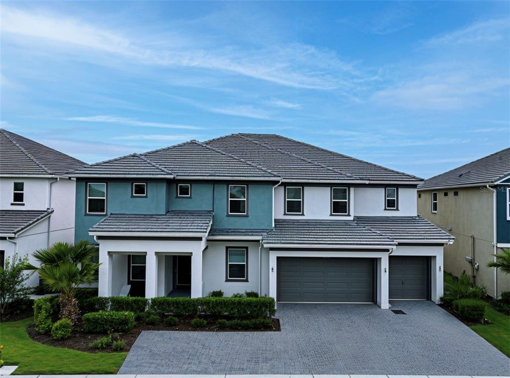 A two-story house with a blue and white exterior, a tiled roof, and a paved driveway — 3880 SONOMA BOULEVARD, KISSIMMEE, FL