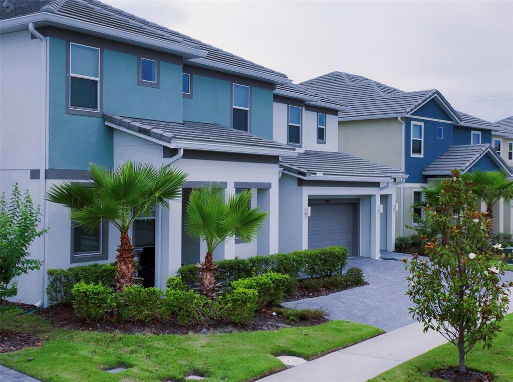 A two-story suburban house with blue and white exterior walls, a garage, and palm trees — 3880 SONOMA BOULEVARD, KISSIMMEE, FL