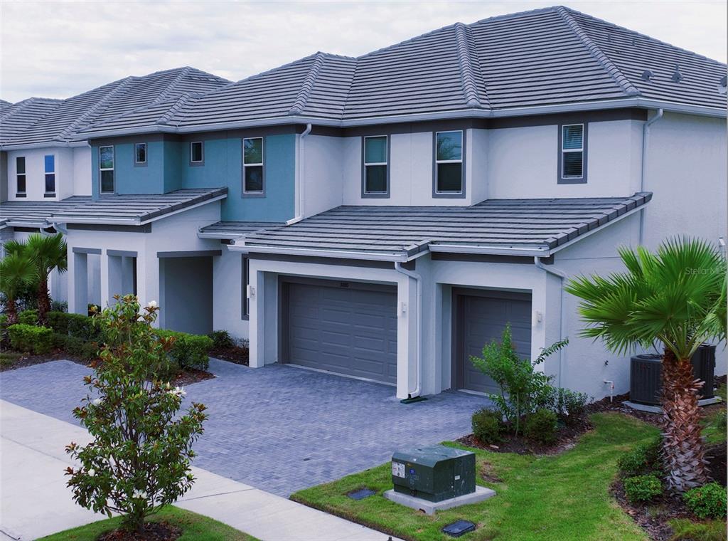 An exterior view of a two-story townhouse with a gray tile roof and paved driveway — 3880 SONOMA BOULEVARD, KISSIMMEE, FL
