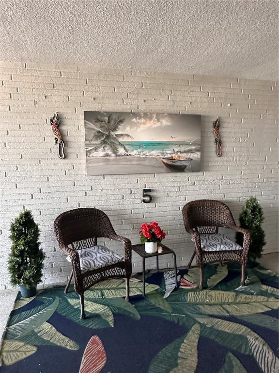 A patio features two wicker chairs, a small table, wall art, and a patterned rug — 5900 SHORE BOULEVARD S UNIT 504, GULFPORT, FL