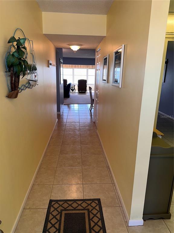 A tiled hallway leads toward a living area with large windows and a view outside — 5900 SHORE BOULEVARD S UNIT 504, GULFPORT, FL