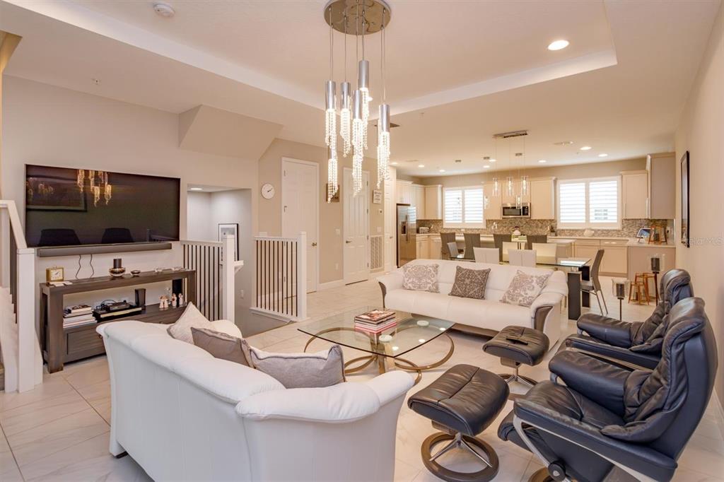 An open-concept living room features white sofas, leather recliners, and a modern crystal chandelier — 1495 LAKE GEORGE DRIVE, LAKE MARY, FL