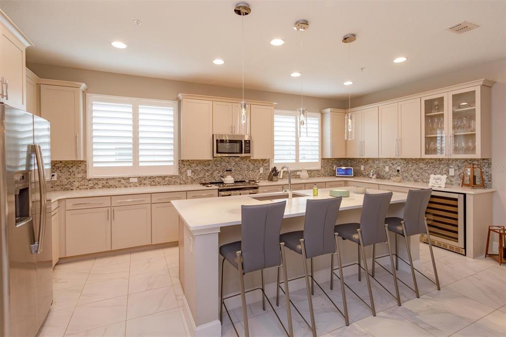 A modern kitchen features light-colored cabinetry, a large central island with bar seating, and tile flooring — 1495 LAKE GEORGE DRIVE, LAKE MARY, FL