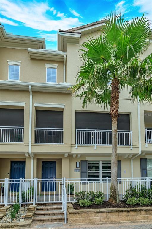 A three-story townhouse exterior features a palm tree, screened balconies, and a white fence — 1495 LAKE GEORGE DRIVE, LAKE MARY, FL