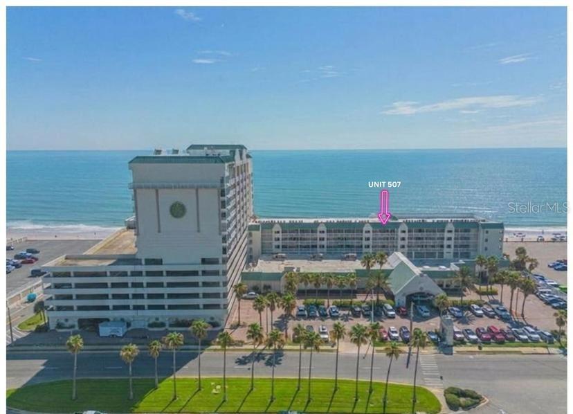 An aerial view of a beachfront resort building with a pink arrow pointing to unit 507 — 2700 N ATLANTIC AVENUE UNIT 507, DAYTONA BEACH, FL