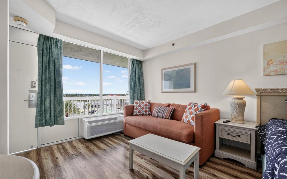 A hotel room features a sofa, coffee table, nightstand, and a balcony with an exterior view — 2700 N ATLANTIC AVENUE UNIT 507, DAYTONA BEACH, FL