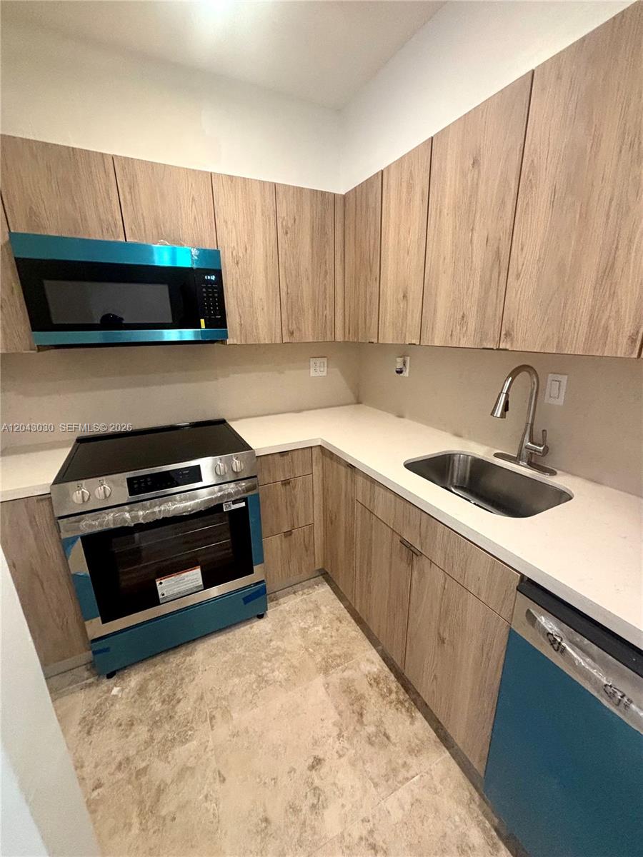 A kitchen features light wood-grain cabinets, a white countertop, and stainless steel appliances — 2666 Tigertail Ave # 114, Miami FL 33133, MIAMI, FL