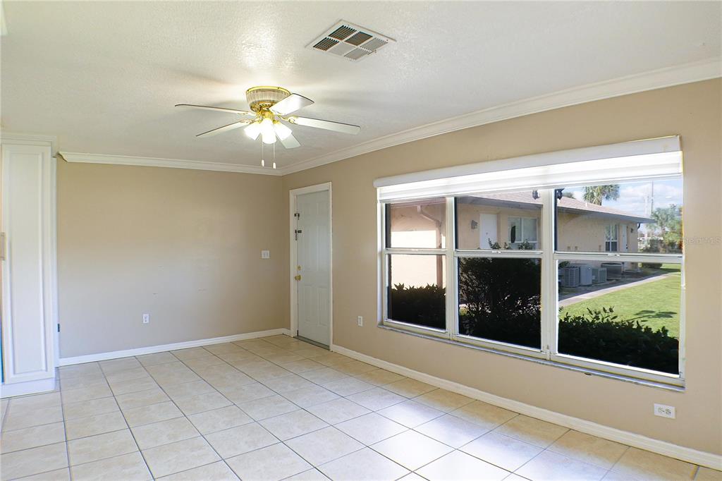 An empty room with beige walls, tile flooring, a ceiling fan, and large windows — 21150 GERTRUDE AVENUE UNIT A3, PORT CHARLOTTE, FL