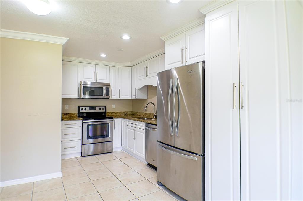 A kitchen with white cabinets, stainless steel appliances, granite countertops, and light-colored tile flooring — 21150 GERTRUDE AVENUE UNIT A3, PORT CHARLOTTE, FL