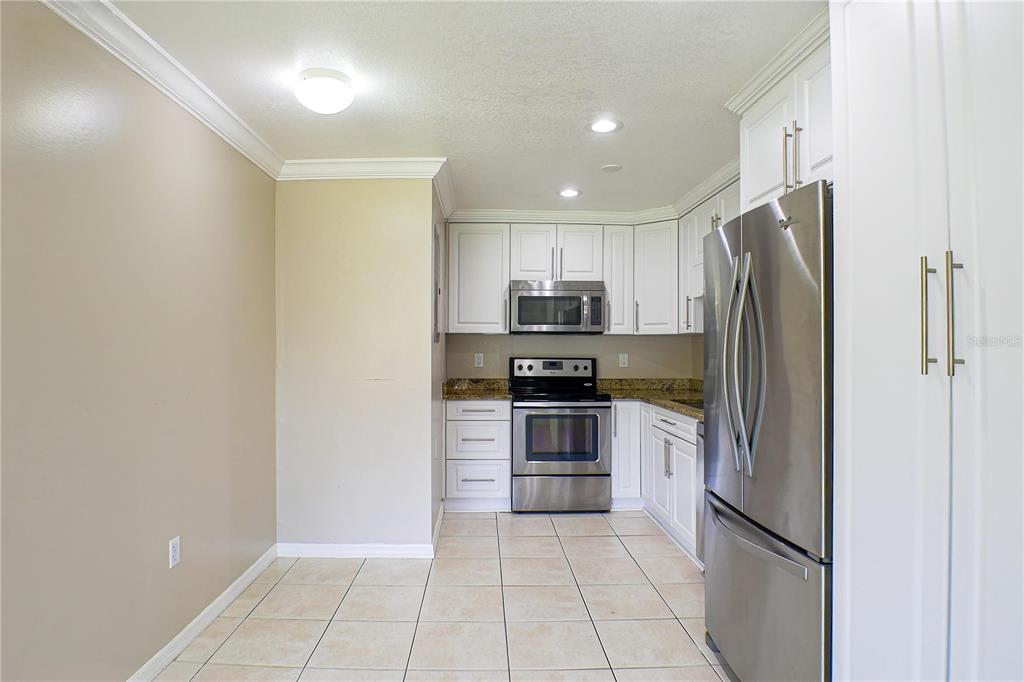 A kitchen with white cabinets, stainless steel appliances, granite countertops, and light-colored tile flooring — 21150 GERTRUDE AVENUE UNIT A3, PORT CHARLOTTE, FL