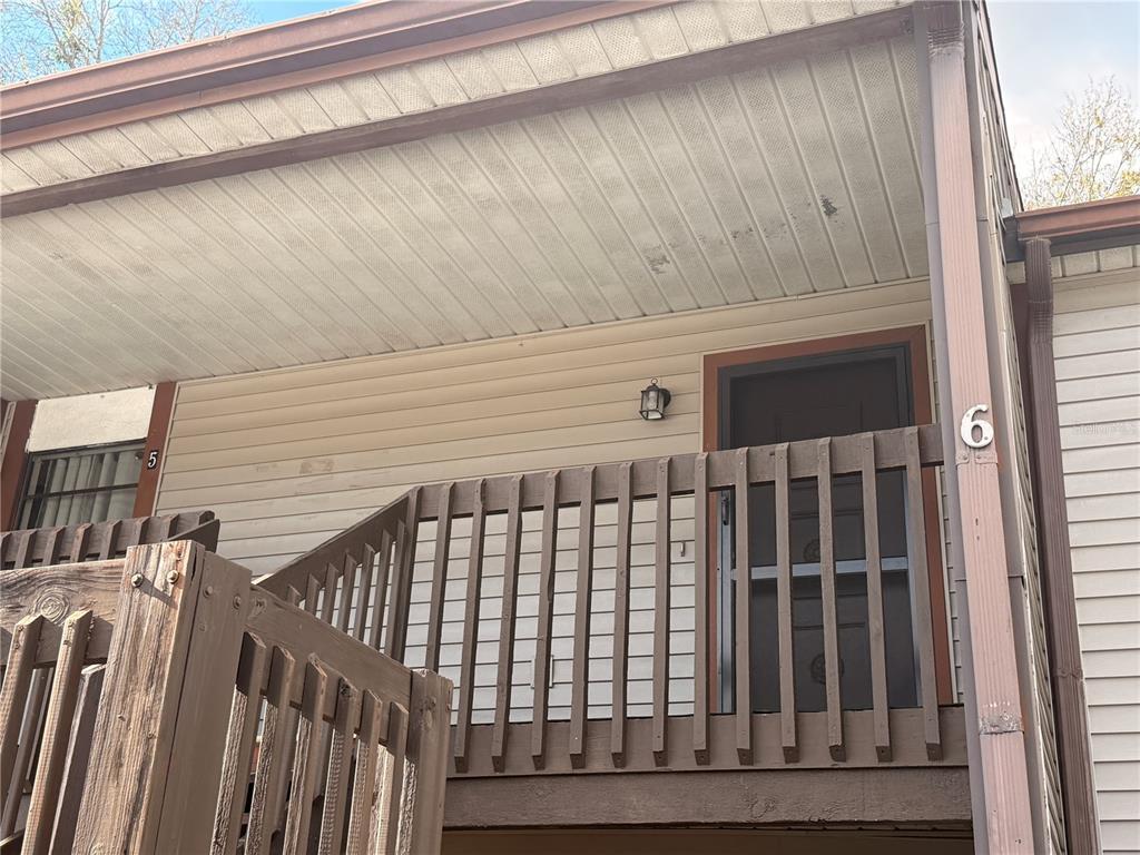 An exterior view shows a wooden staircase leading to a second-story balcony with unit number six — 12155 ENVIRONMENTAL DRIVE UNIT 6, NEW PORT RICHEY, FL