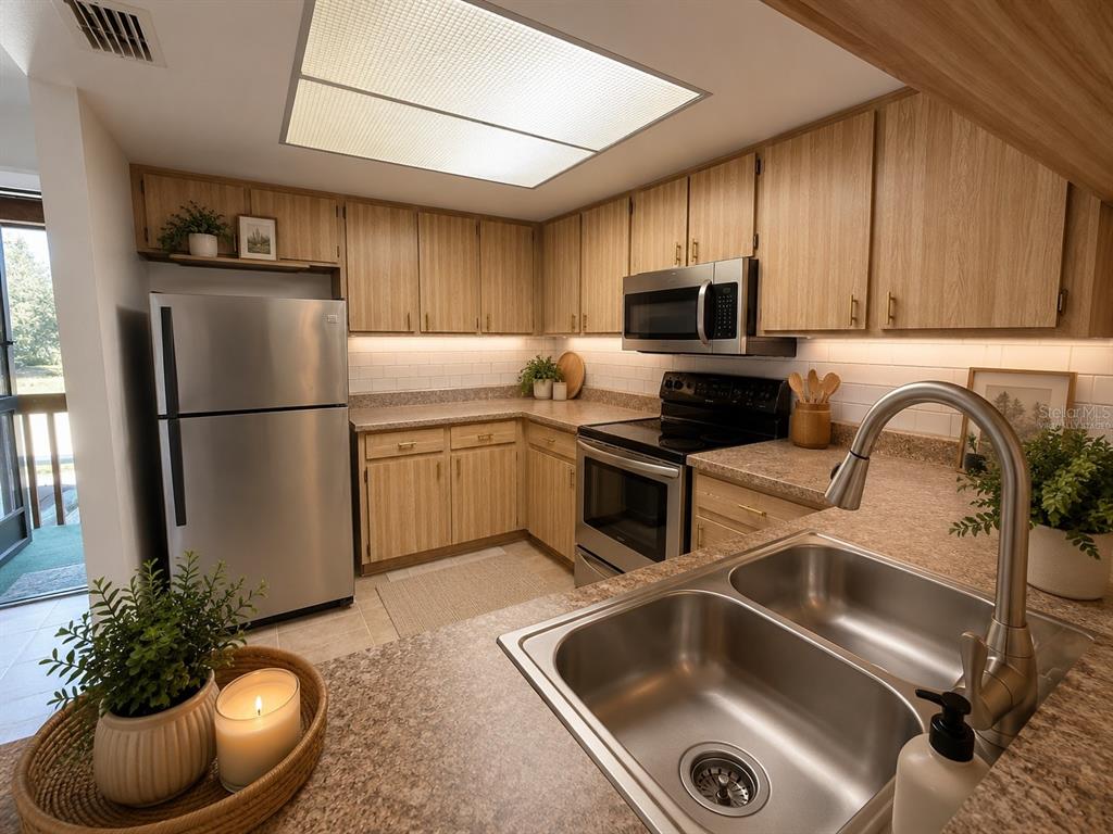 A kitchen features light wood cabinets, stainless steel appliances, and a double-basin sink — 12155 ENVIRONMENTAL DRIVE UNIT 6, NEW PORT RICHEY, FL