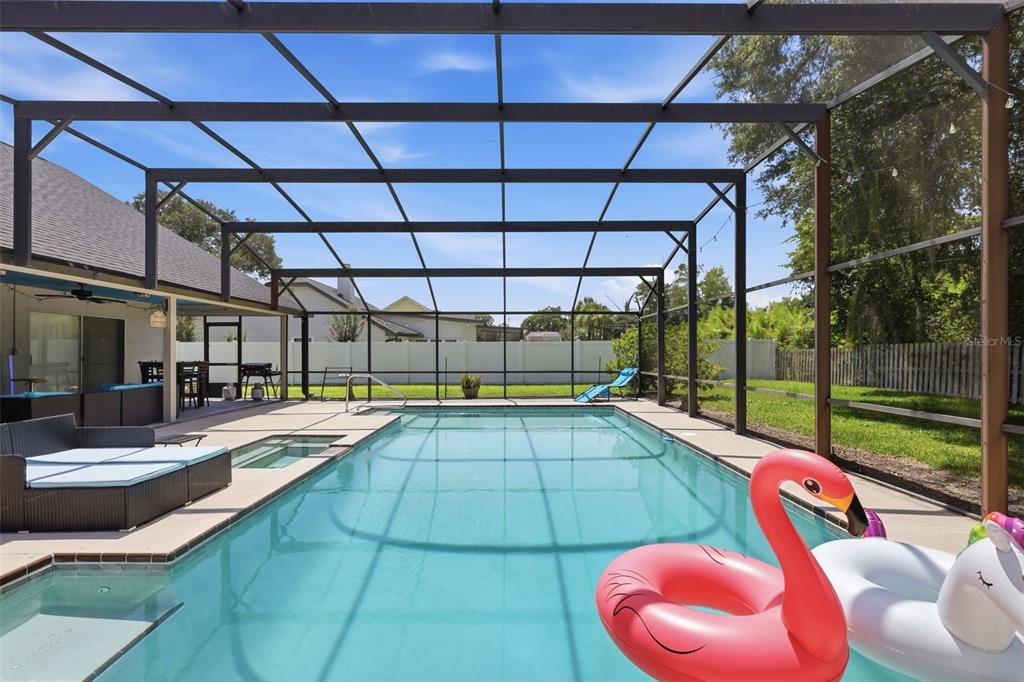A screened-in swimming pool and spa area with patio furniture and inflatable pool floats — 1055 CHESTERFIELD CIRCLE, WINTER SPRINGS, FL