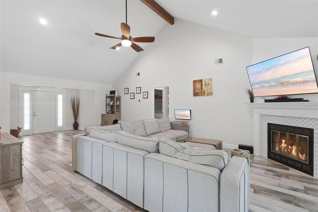 A living room with a vaulted ceiling, a sectional sofa, a fireplace, and wood-look flooring — 1055 CHESTERFIELD CIRCLE, WINTER SPRINGS, FL