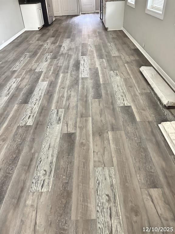A room with gray wood-look plank flooring and white baseboards — 602 NW 1ST AVENUE, MULBERRY, FL