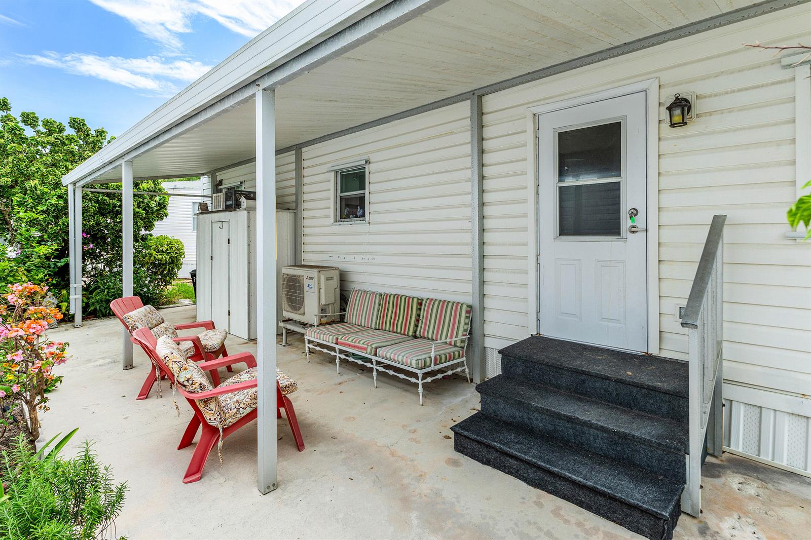 A covered concrete patio features outdoor seating, a white door, and a mini-split air conditioner — 7 Ruthmary Avenue # F, Briny Breezes FL 33435, BRINY BREEZES, FL