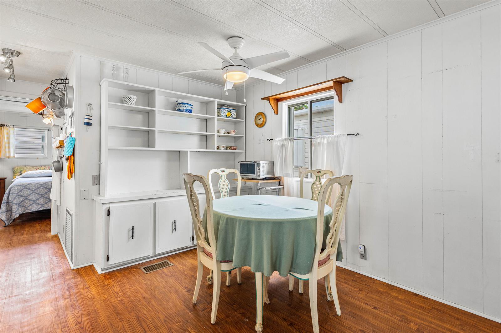 A dining area features a round table, four chairs, white built-in shelving, and wood flooring — 7 Ruthmary Avenue # F, Briny Breezes FL 33435, BRINY BREEZES, FL
