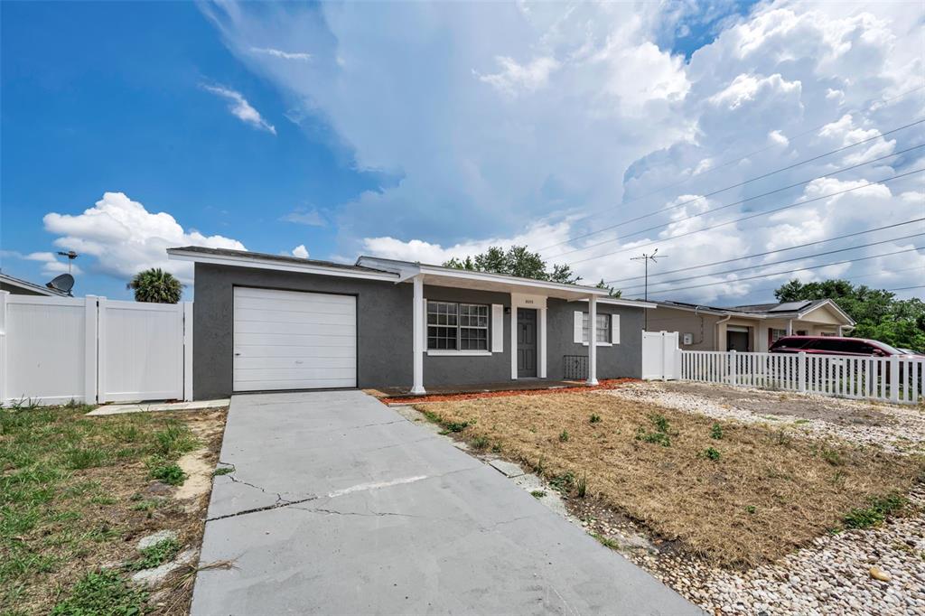 A single-story house with a gray exterior, a white garage door, and a concrete driveway — 8053 DEDHAM DRIVE, PORT RICHEY, FL
