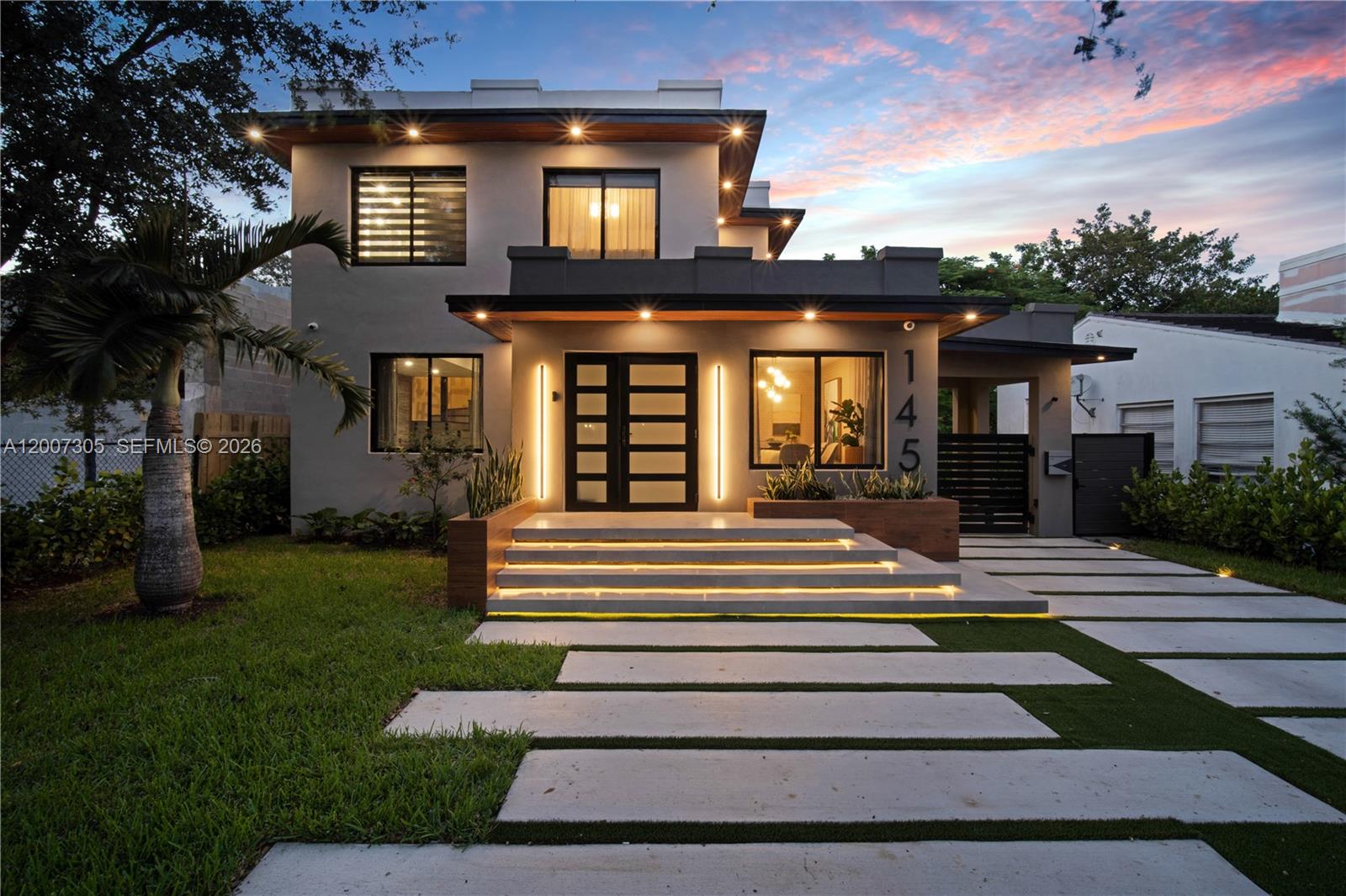 A modern two-story house features a lit entryway with concrete steps and a paved driveway — 145 NE 49th St # A, Miami FL 33137, MIAMI, FL
